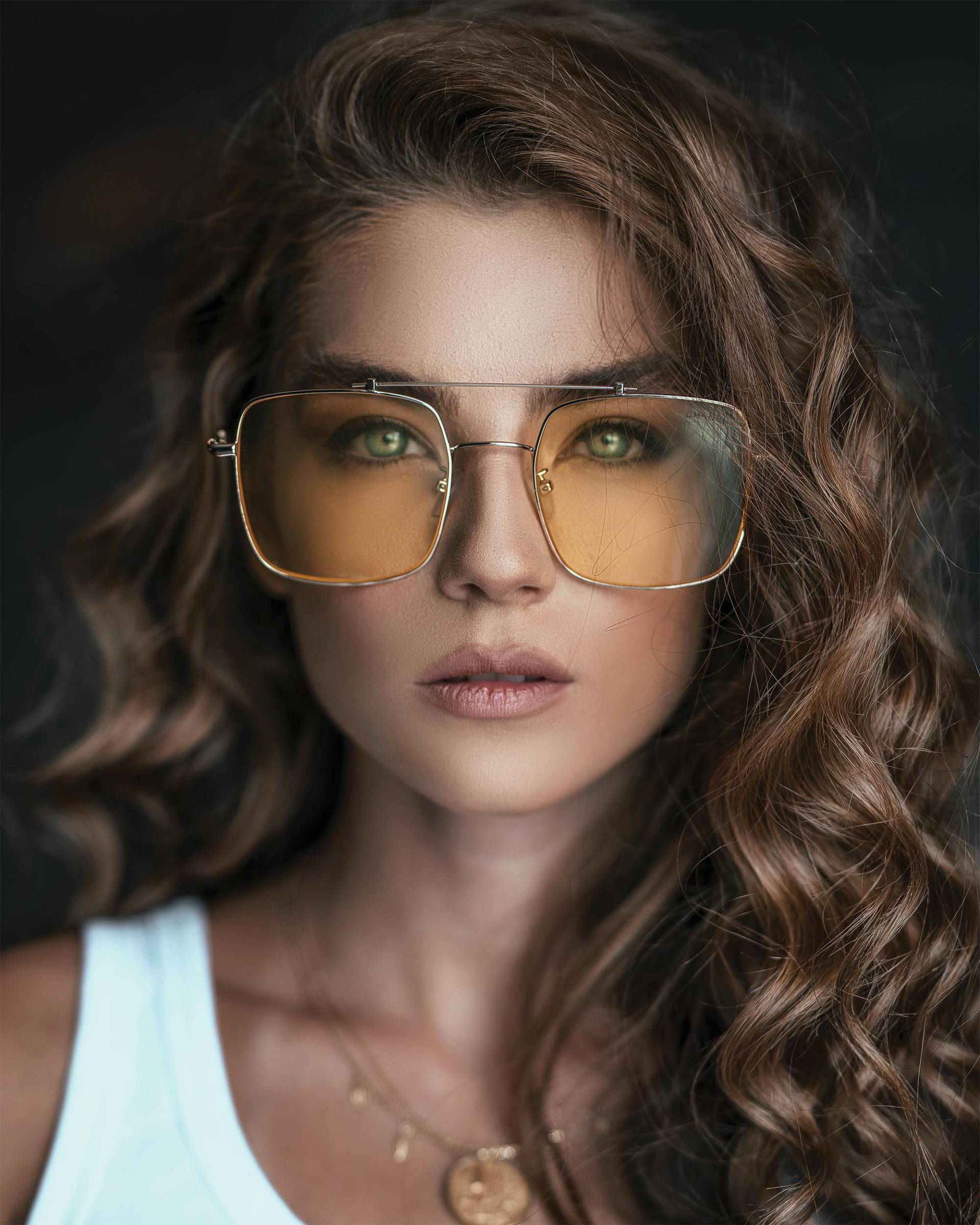 Beautiful woman with curly hair wearing stylish sunglasses and a chic outfit.